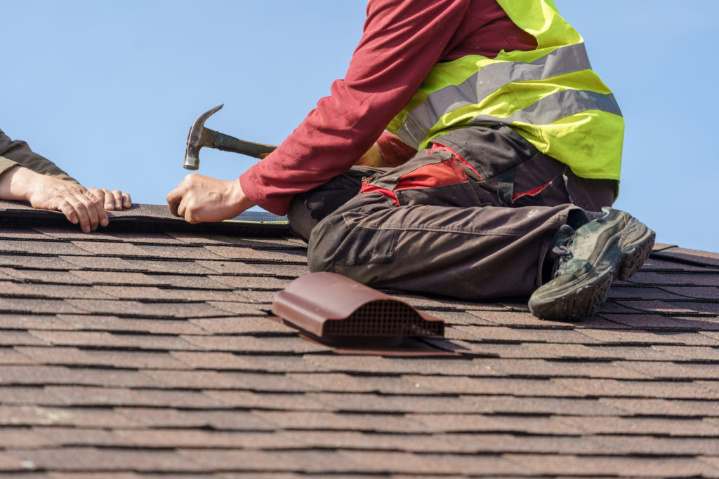 Image of roofer nailing down a roof cap on a multifamily home