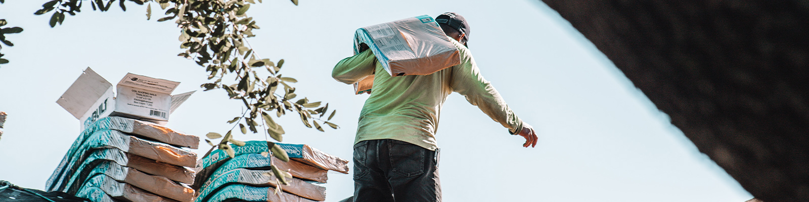 man carrying shingles on a residential roof